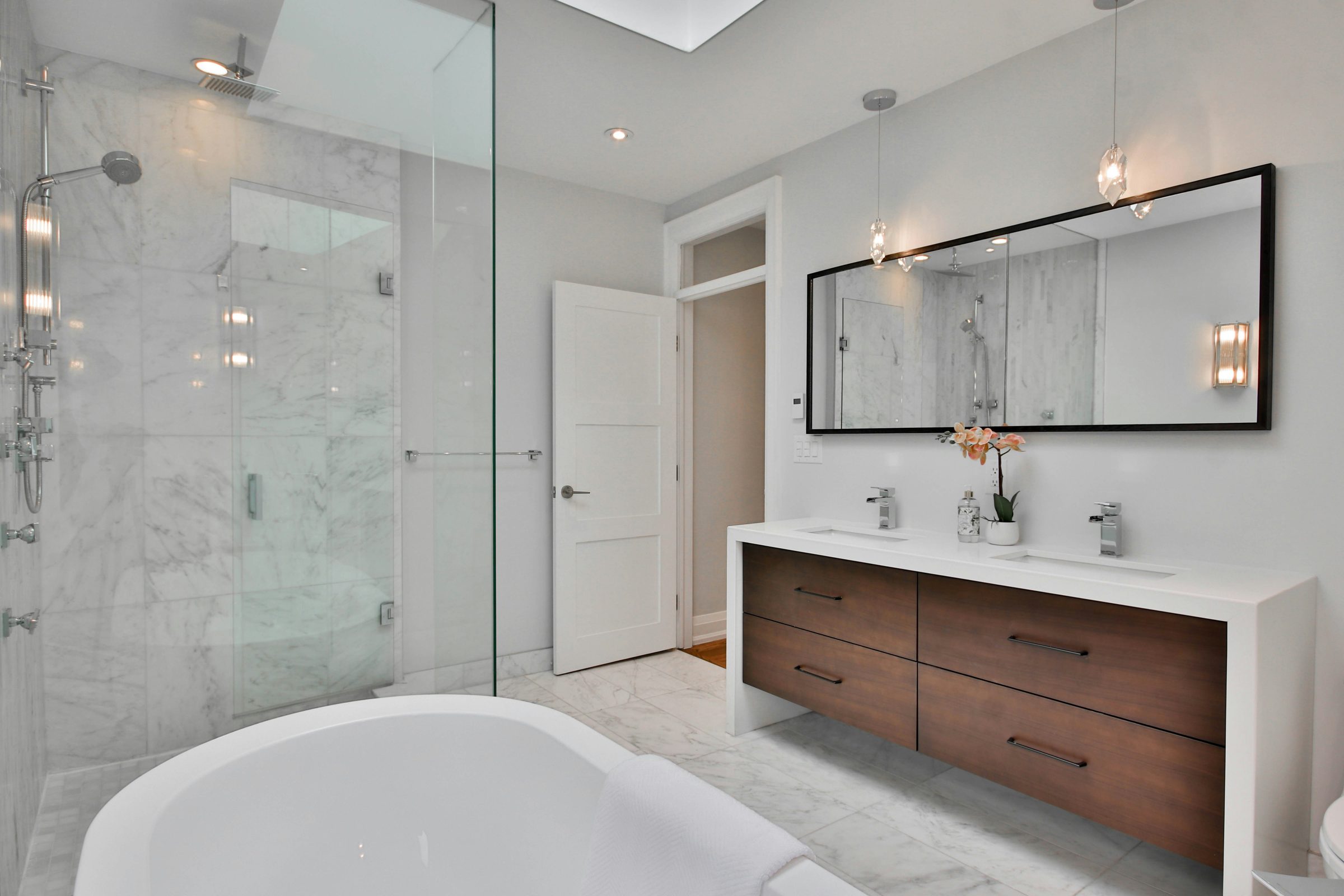 Modern remodeled bathroom with a freestanding tub and walnut floating vanity