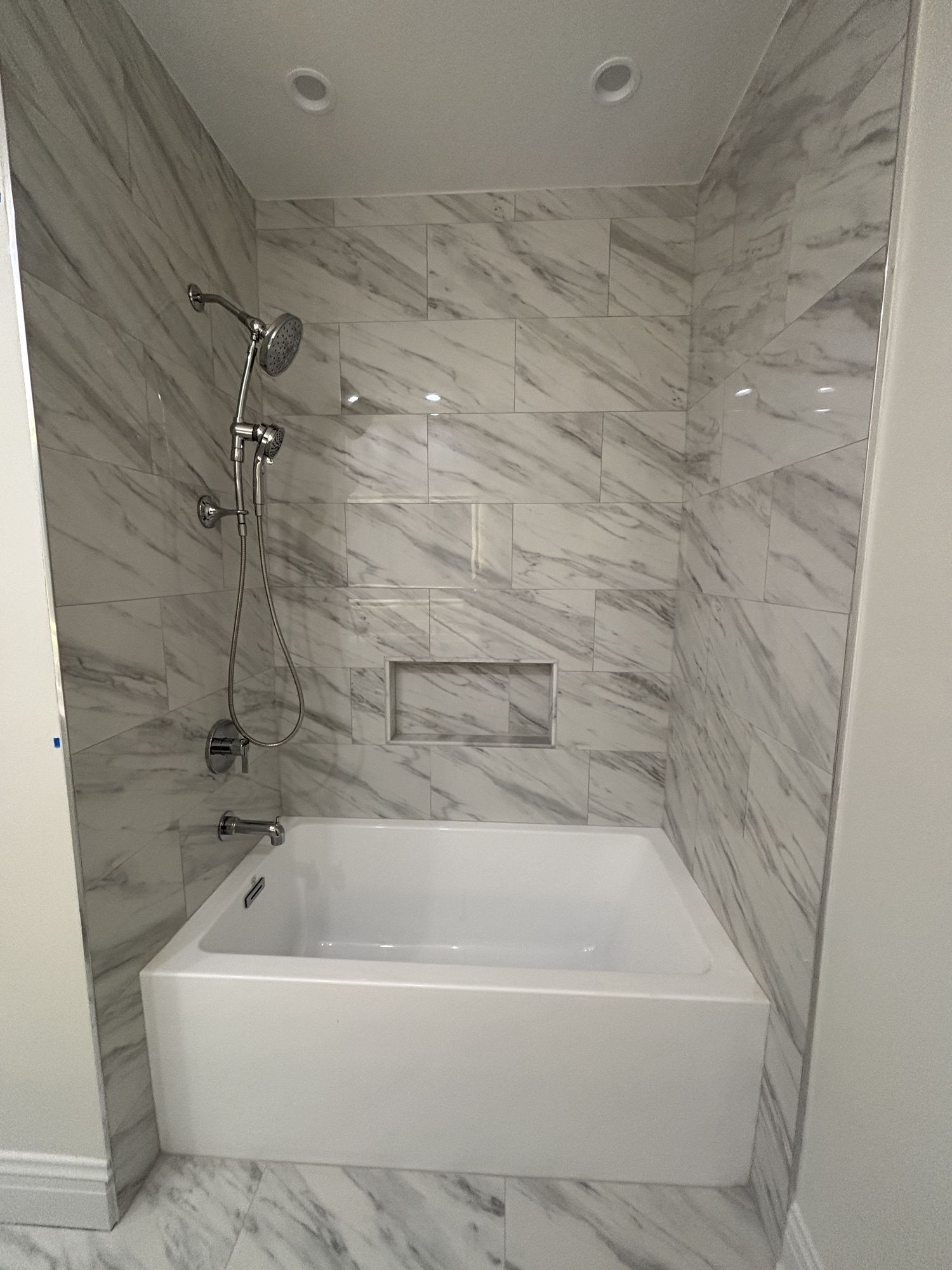 Wider view of the Carrara-look marble tub alcove and deck-mounted fixtures