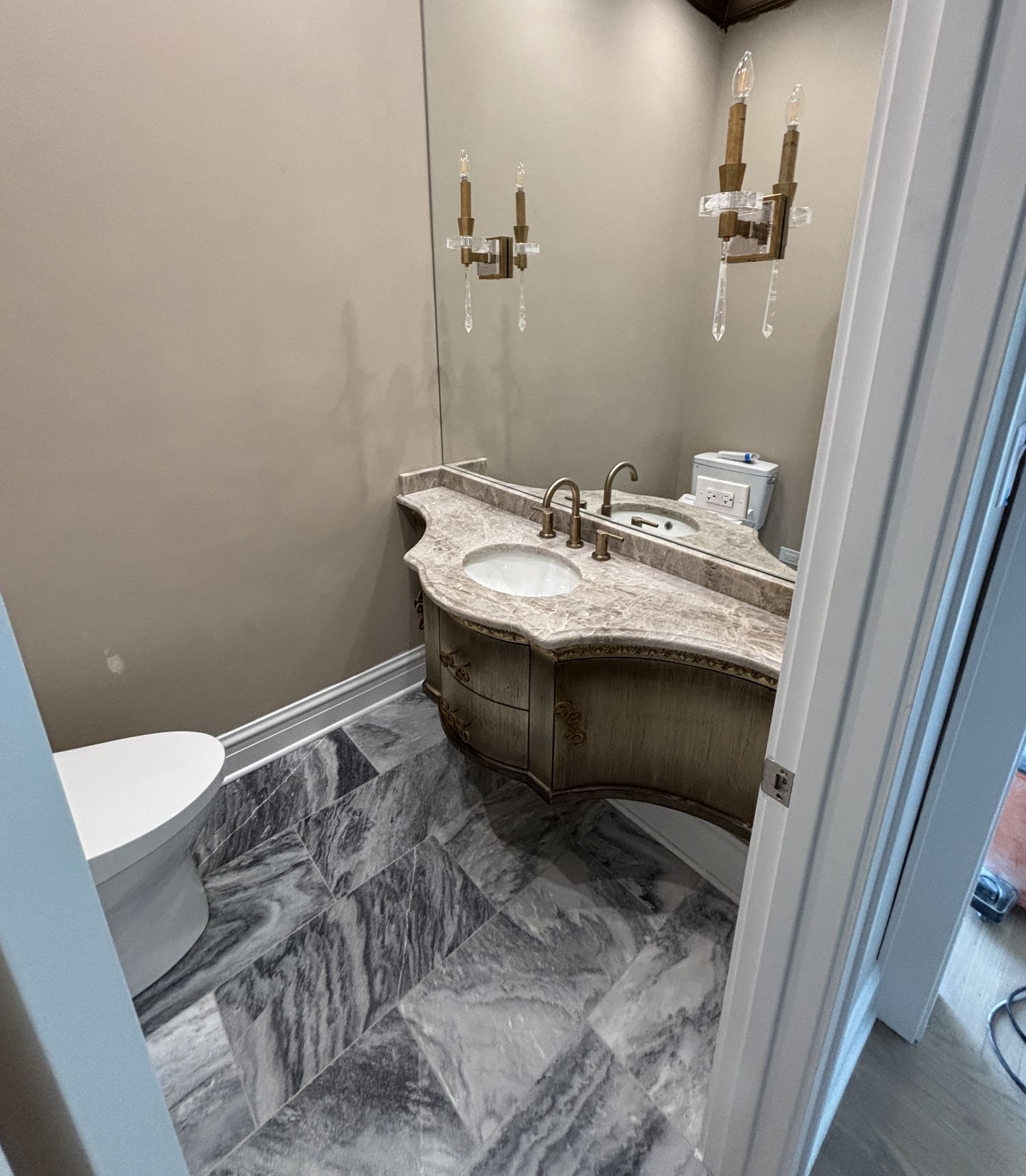 Powder room with a custom-built furniture-style vanity, custom granite top, crystal-and-brass sconces, and a diagonal marble floor