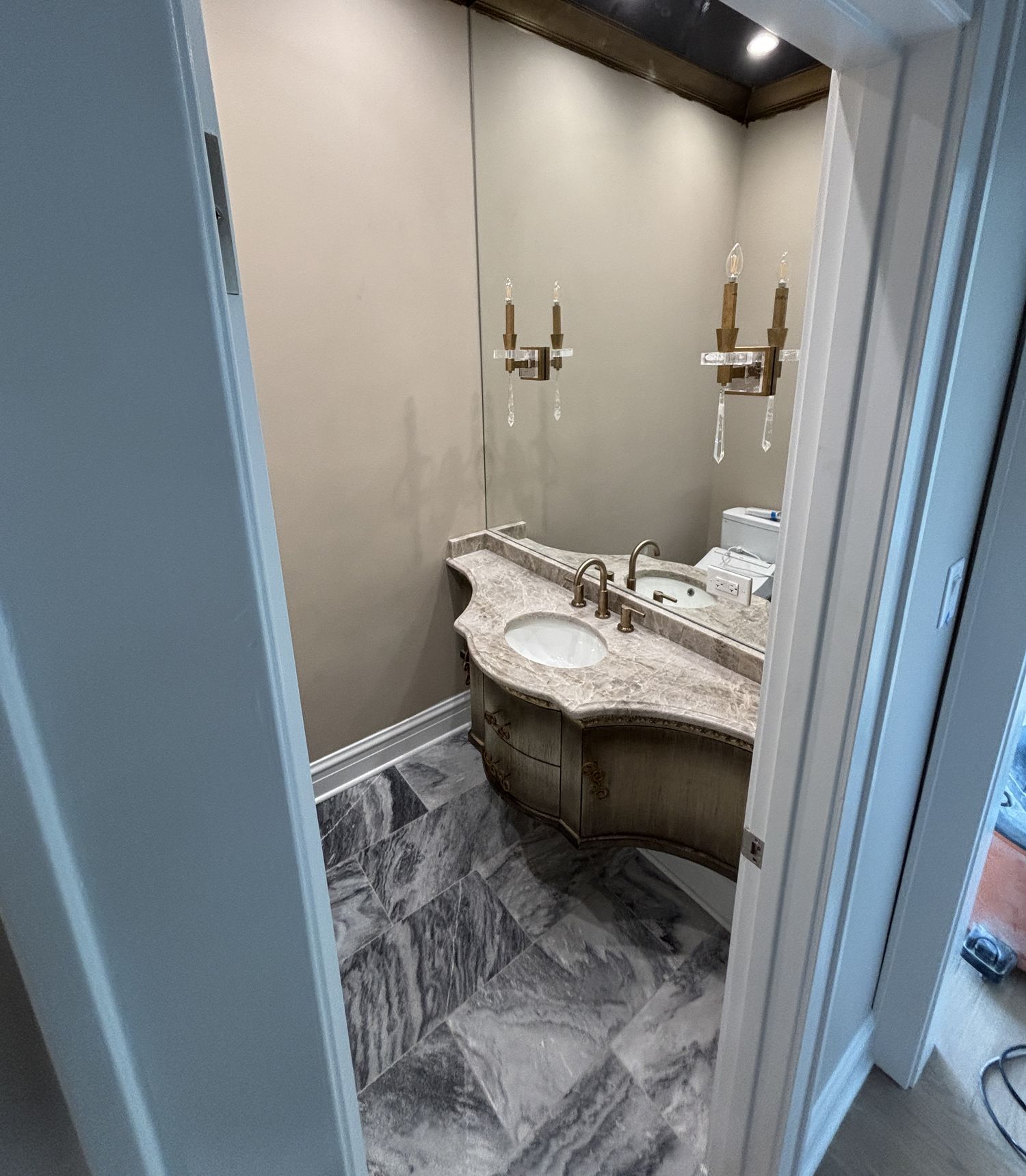 Angle of the custom vanity showing the diagonal marble floor and brass fixtures