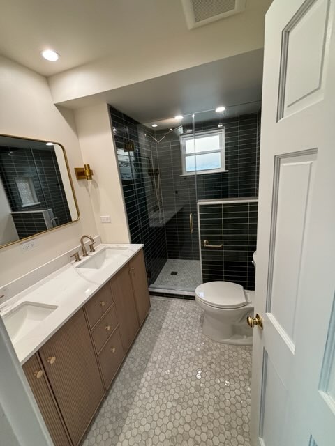 Bathroom with glass shower enclosure, fluted wood vanity, and marble counter