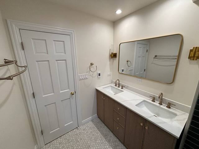 Double vanity with fluted wood cabinets, marble counter, and a wide brass-framed mirror