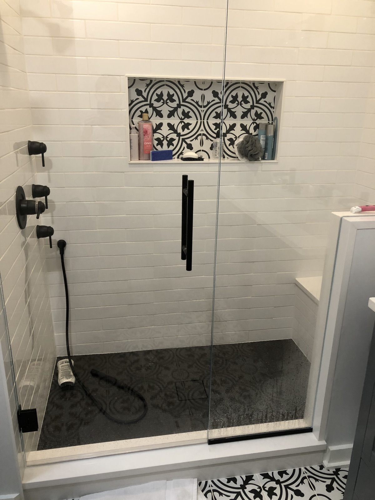 Walk-in shower with white subway tile, patterned tile niche, and matte black fixtures
